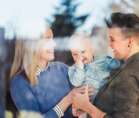 A woman holding a baby and another woman standing next to them.