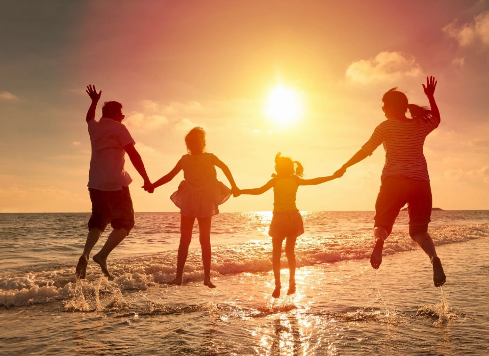 A family is jumping in the water at sunset.