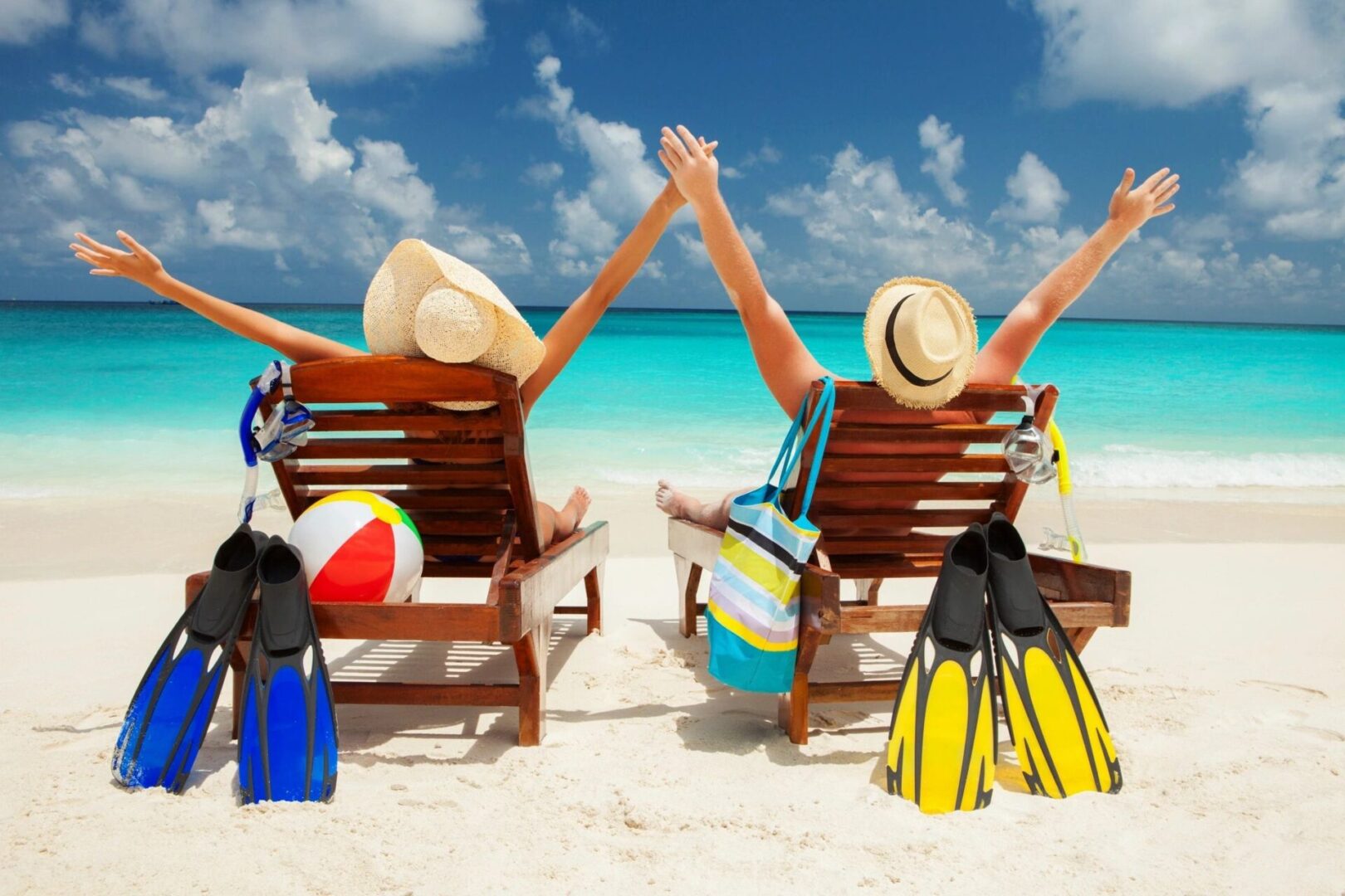 Two people sitting on beach chairs with arms up
